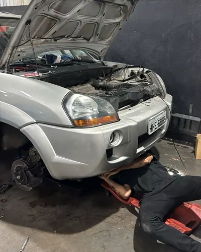 Mecânico da LF trabalhando embaixo de um SUV com a roda dianteira desmontada